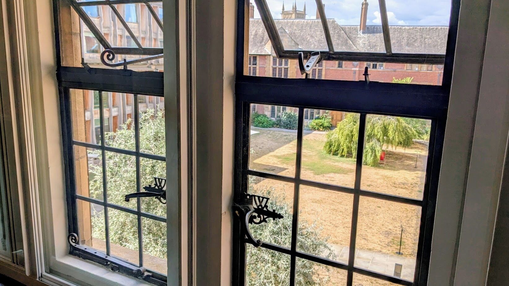 A window with a metal grid design and a lock mechanism.