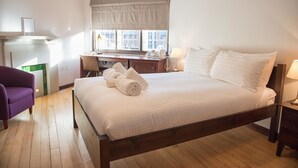 A bedroom with a wooden bed, a desk, a chair, and a window with curtains. - West Court - Cambridge - Campus Accommodation (Cambridge)