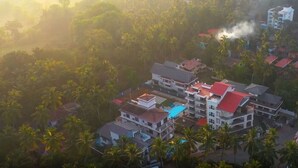 A residential area with multi-story buildings, a swimming pool, and dense palm trees. - 10 Bedroom Private Pool Villa in Calangute with Jacuzzi, Kids Pool, Mini Golf (Calangute)