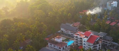 A residential area with multi-story buildings, a swimming pool, and dense palm trees.