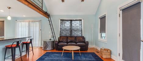 A living room with a blue rug, a brown leather sofa, and a wooden coffee table.