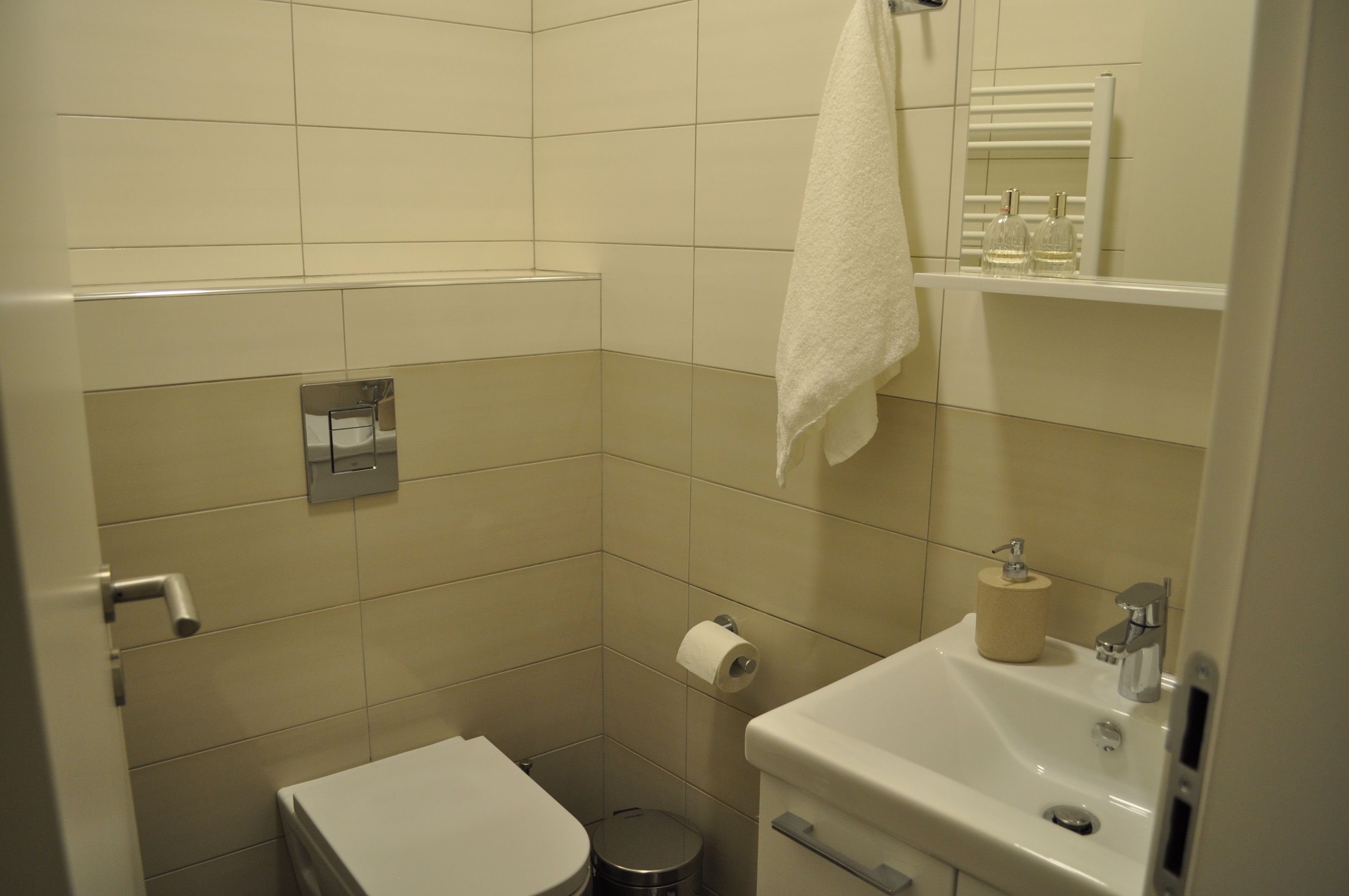 A small, clean bathroom with a toilet, sink, and mirror.