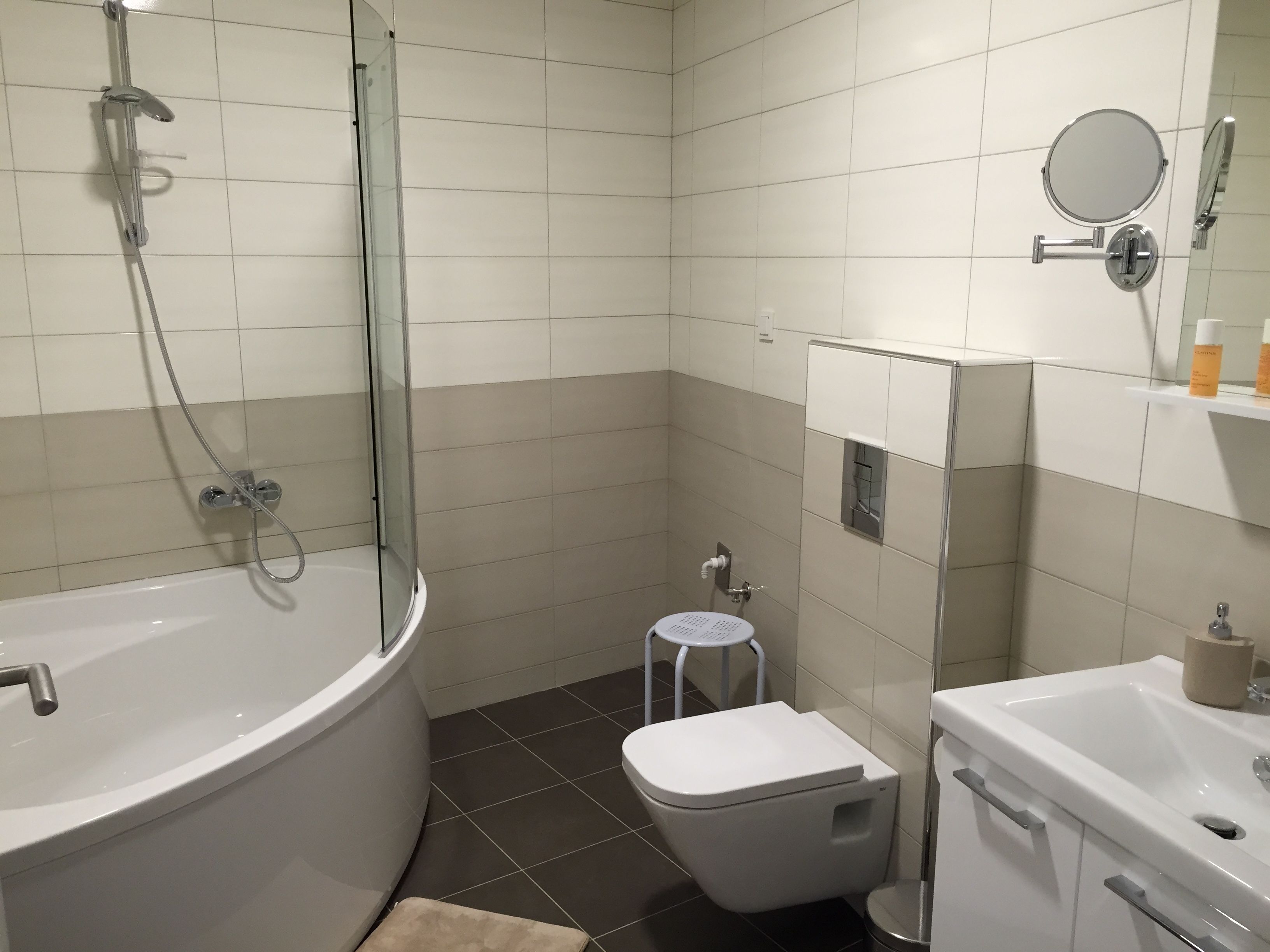 Une salle de bain avec une baignoire, des toilettes et un petit tabouret.
