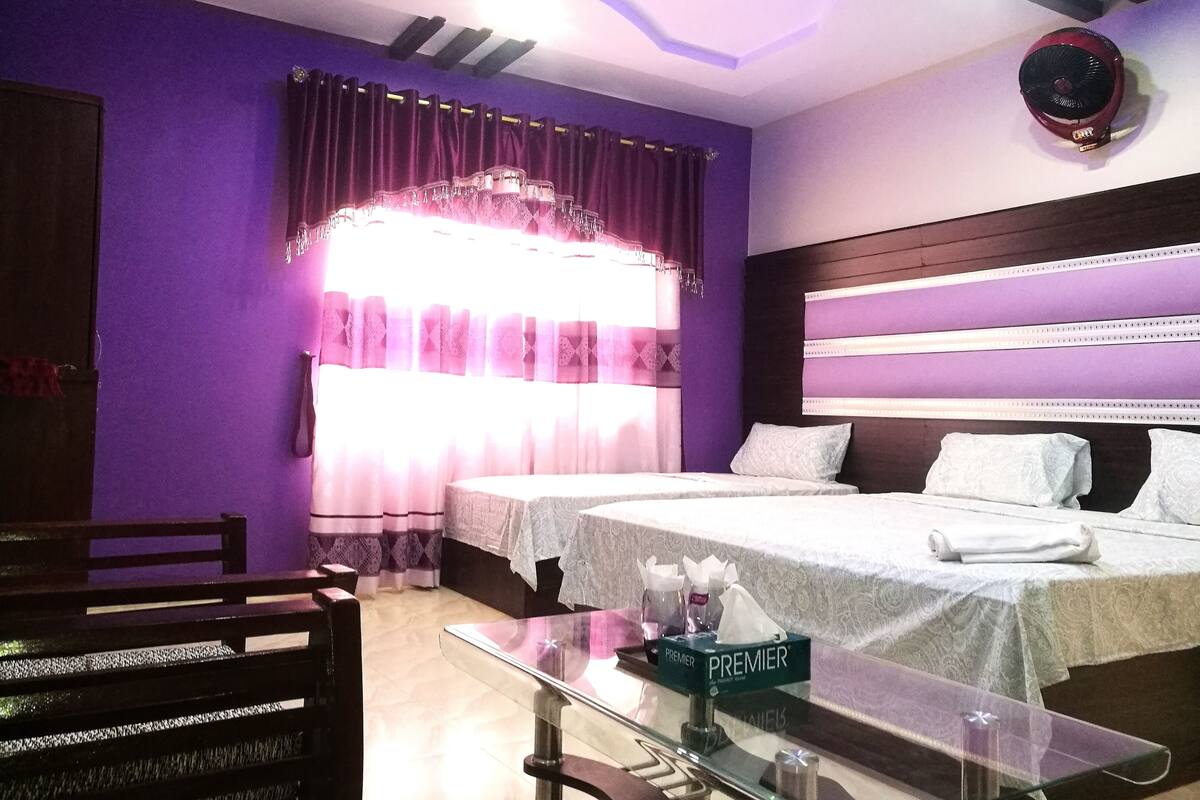 Habitación de hotel con dos camas, una mesita de vidrio y una mesita de noche con caja de pañuelos.