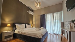 A bedroom with a bed, bedside lamps, a ceiling light, a TV, a plant, and a window with curtains. - Homely Stay at Acropolis Museum (Athens)