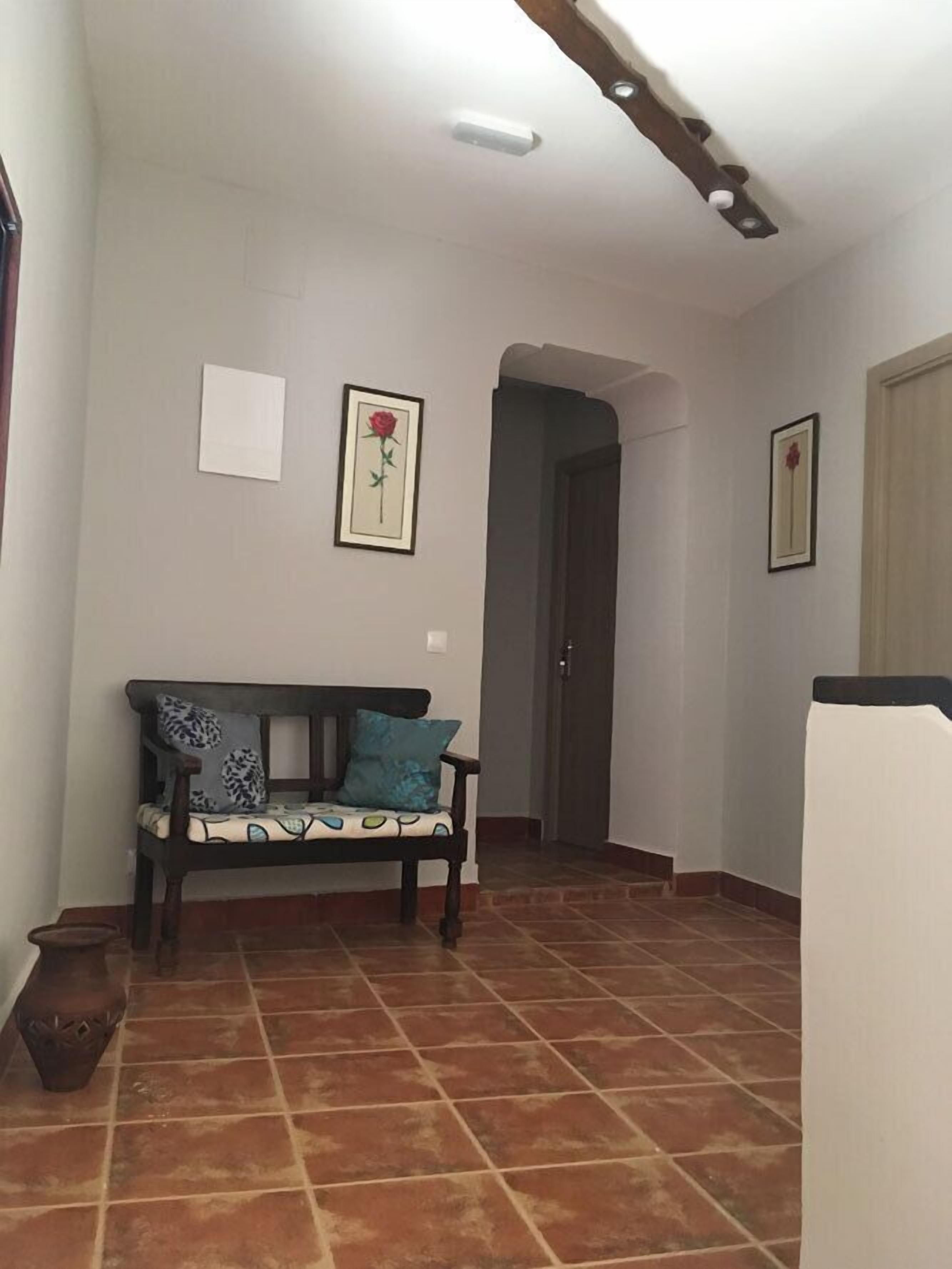 A hallway with a bench, tiled floor, and framed pictures on the walls.