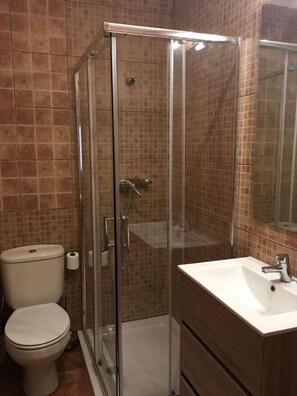 A bathroom with a glass-enclosed shower, a toilet, and a sink. - Casa Rural Las Violetas (Villanueva de los Infantes)