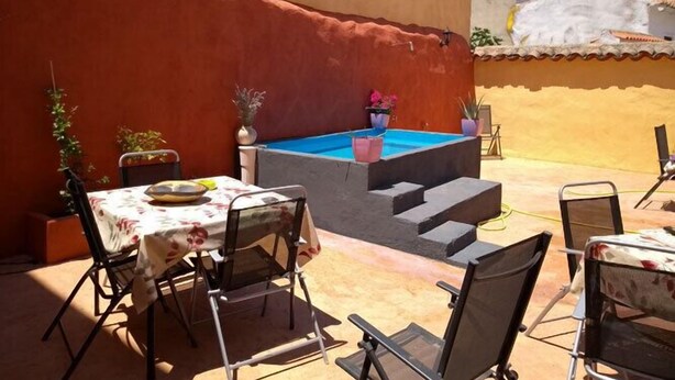A sunlit outdoor patio with a pool, chairs, and a table set for dining. - Casa Rural Las Violetas (Villanueva de los Infantes)