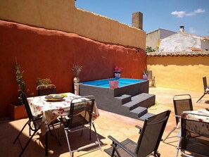 A sunlit outdoor patio with a pool, chairs, and a table set for dining. - Casa Rural Las Violetas (Villanueva de los Infantes)