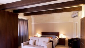 A bedroom with a bed, two bedside lamps, a wooden wardrobe, a sofa, and a small table. - Girgentina (Xaghra)