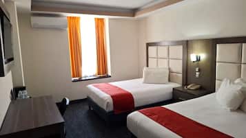 Una habitación de hotel con dos camas, un escritorio y una ventana con cortinas.