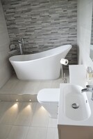 Un baño moderno con una bañera independiente, inodoro y lavamanos.
