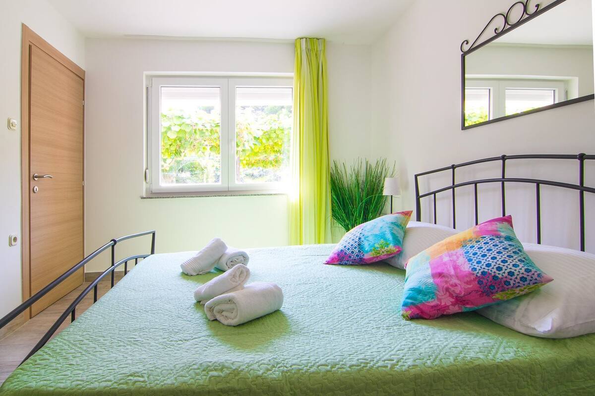 Una camera da letto con un letto, una finestra con tende, uno specchio e una porta.