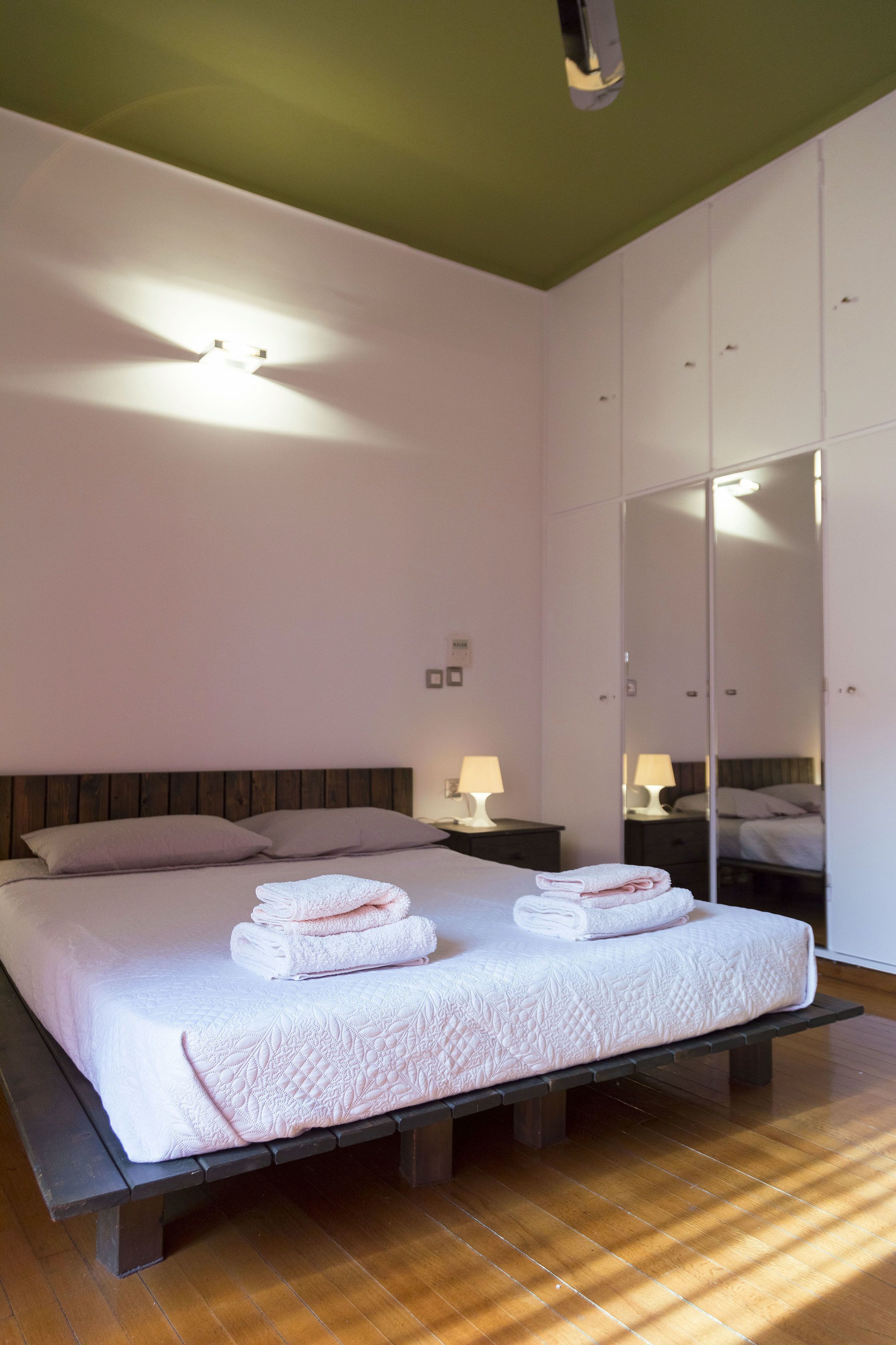 Habitación de hotel con una cama grande, dos mesitas de noche con lámparas, un espejo y un armario.
