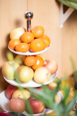 A three-tiered fruit stand with oranges and apples.