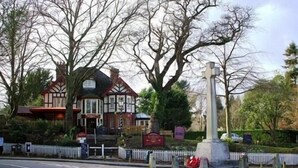 A traditional building with a prominent entrance, a small garden area with a monument, and a white picket fence. - The Burley Inn (Ringwood)