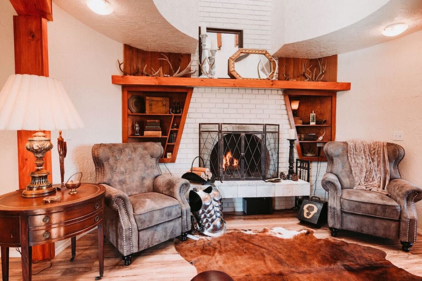 Una sala de estar acogedora con chimenea, sillones de cuero, una mesa de centro de madera y un manto de piel.