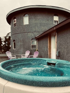Un edifici de planta circular amb una piscina i tres cadires Adirondack.