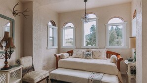 A bedroom with a large bed, a chair, a bedside table, and a mirror. - Sequim Lavender Castle (Sequim)