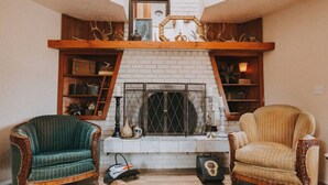 A cozy living room with a fireplace, two upholstered chairs, and a leather sofa. - Sequim Lavender Castle (Sequim)