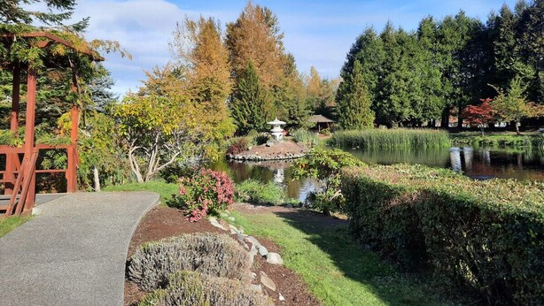 A garden with a pond, a wooden pergola, and a stone pathway. - Sequim Lavender Castle (Sequim)