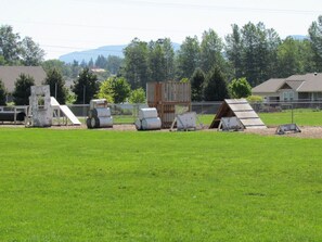 A fenced outdoor area with various structures, including a wooden shed and a metal frame structure. - Sequim Lavender Castle (Sequim)