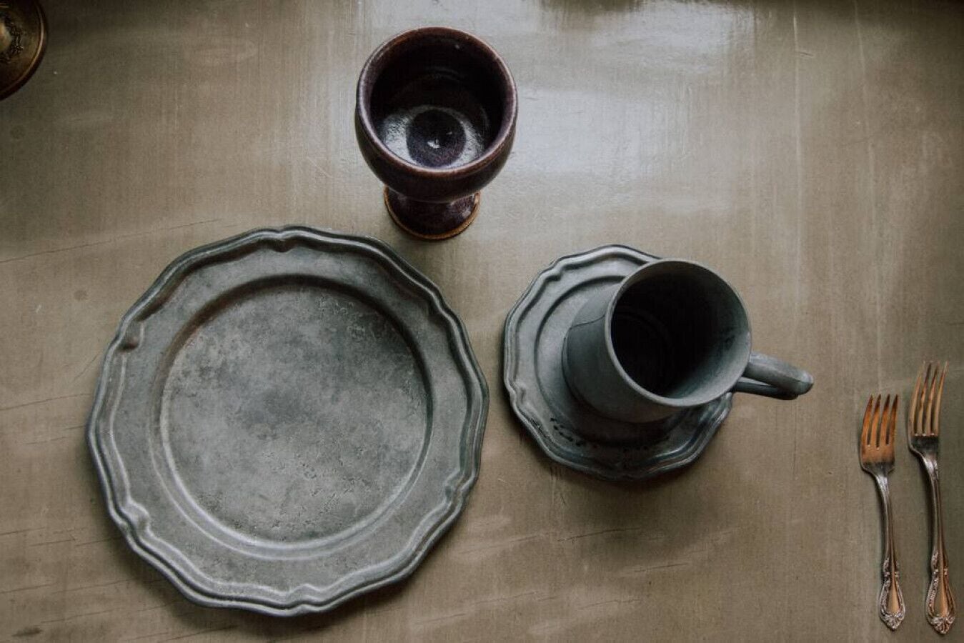 Un tavolo con un piatto, una tazza e due forchette.