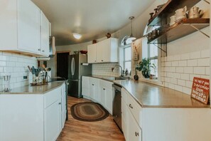 A modern kitchen with white cabinets, a stainless steel refrigerator, and a wooden floor. - Sequim Lavender Castle (Sequim)