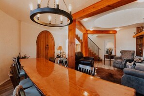 A spacious living room with a large wooden dining table, leather sofas, and a staircase leading to an upper level. - Sequim Lavender Castle (Sequim)