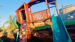A wooden play structure with a slide and climbing steps. - Sequim Lavender Castle (Sequim)