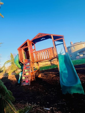 A wooden play structure with a slide and climbing steps. - Sequim Lavender Castle (Sequim)