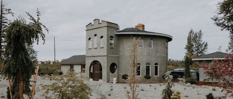 A circular stone building with a tower, arched windows, and a central chimney.