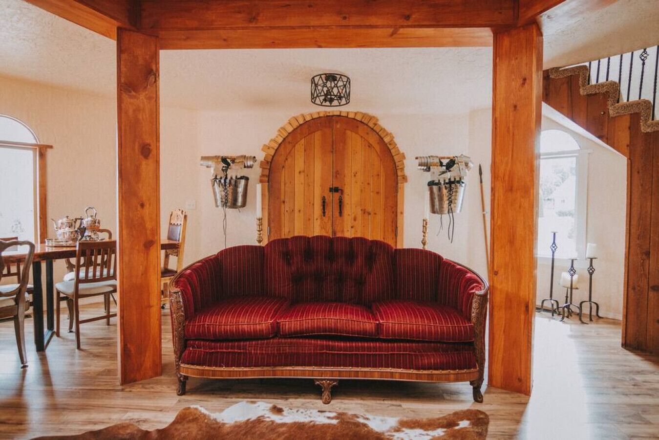 A cozy room with a red striped sofa, wooden beams, a wooden door, and a cowhide rug.