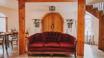 A cozy room with a red striped sofa, wooden beams, a wooden door, and a cowhide rug.