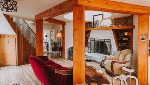 A spacious living area with a red velvet sofa, a wooden coffee table, and a fireplace. - Sequim Lavender Castle (Sequim)