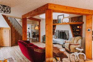 A spacious living area with a red velvet sofa, a wooden coffee table, and a fireplace. - Sequim Lavender Castle (Sequim)