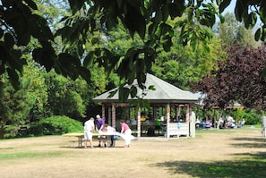 Un pavelló al parc amb una taula de pícnic i persones a prop.