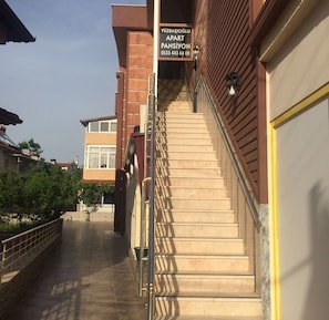Eine Treppe führt zu einem Mehrfamilienhaus, auf dem ein Schild als Wohnungskomplex gekennzeichnet ist.
