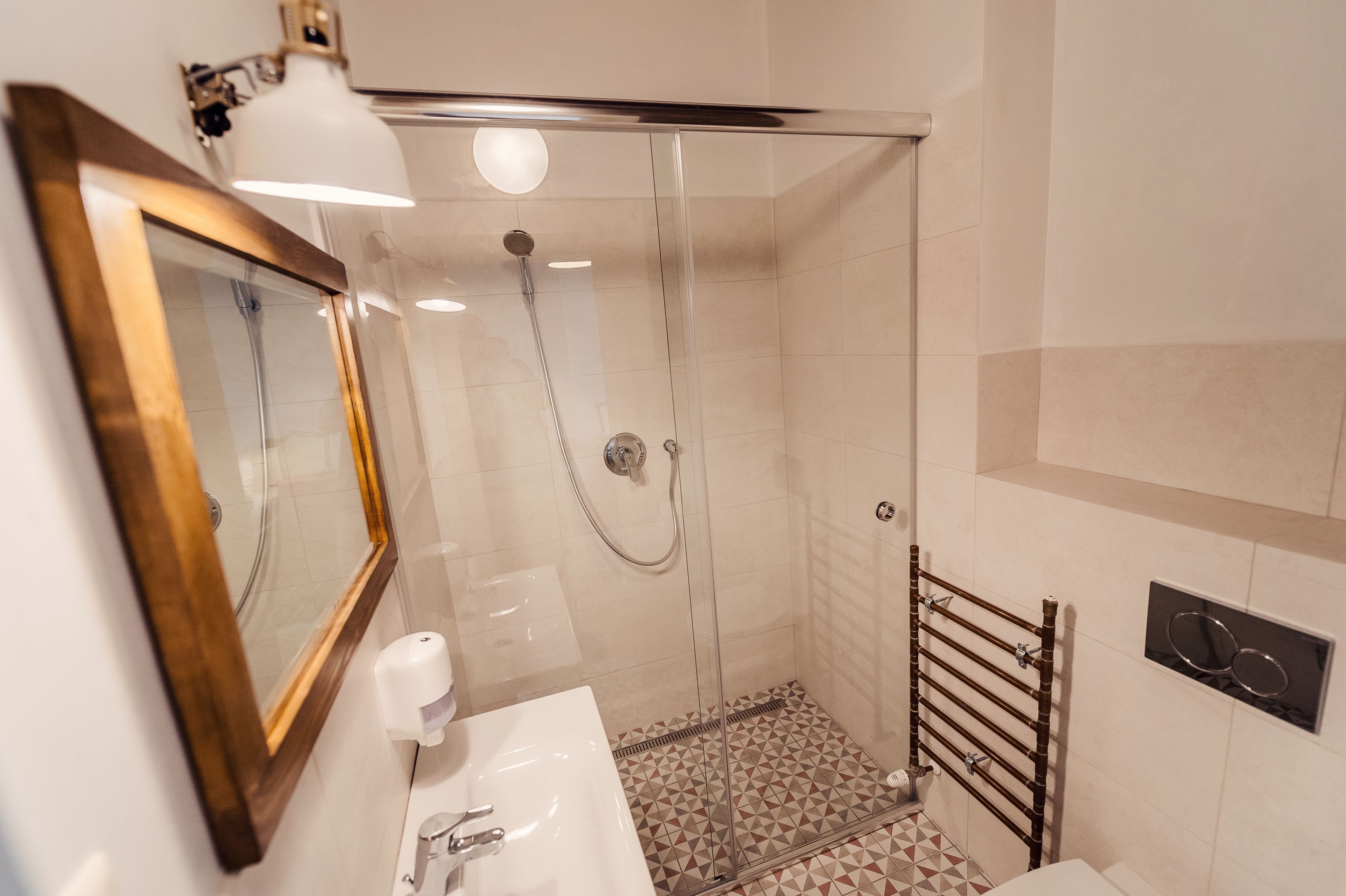 A modern bathroom with a glass-enclosed shower, a wooden-framed mirror, and a white sink.