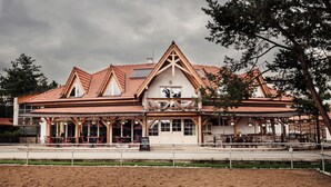 A building with a pitched roof, large windows, and a covered outdoor seating area. - Pension Zwicker (Lubotice)