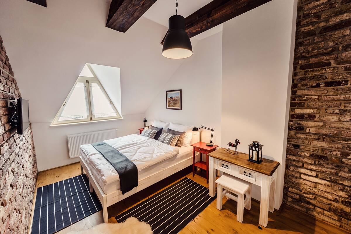 Ein Schlafzimmer mit Bett, Nachttisch, Lampe und einem Fenster mit Blick.