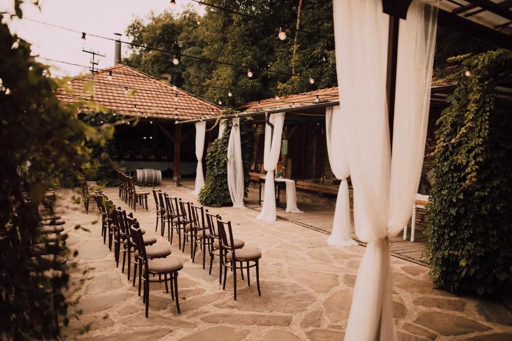 An outdoor seating area with stone flooring and wooden chairs arranged in rows.