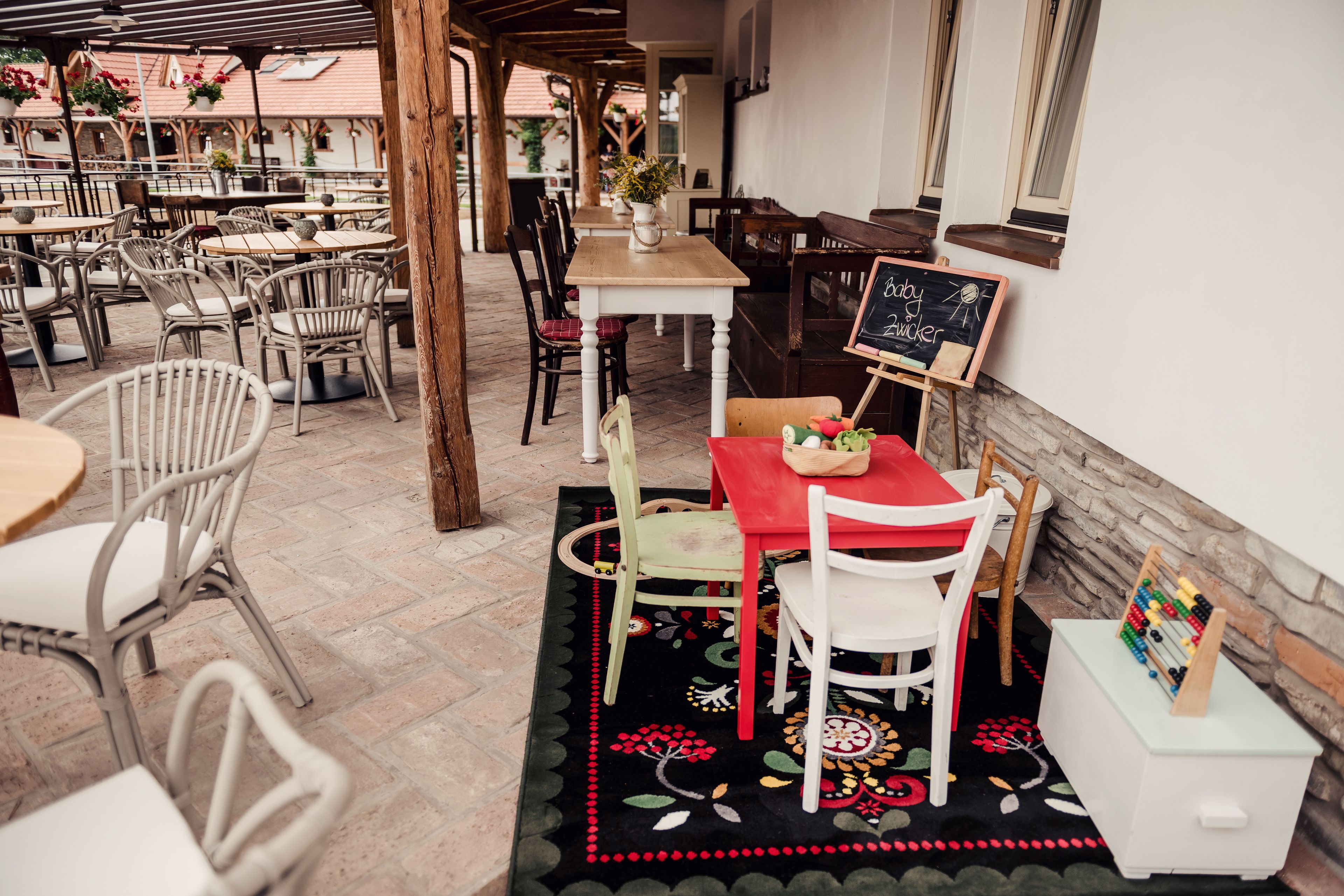 A restaurant with outdoor seating, including tables and chairs, and a chalkboard menu.