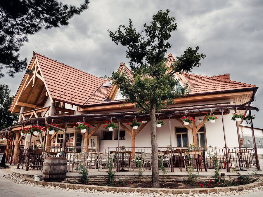 A rustic building with a tiled roof, wooden beams, and outdoor seating.