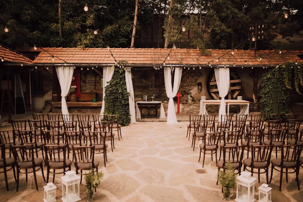 An outdoor event space with stone flooring, wooden chairs, and tables arranged for an event.