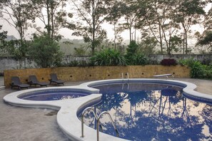 Una piscina al aire libre, sillones reclinables de piscina