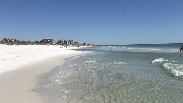 A beach with clear shallow waters, a sandy shore, and buildings in the background. - Fantastic Beach location! With Ocean View.1 Bedroom, Bunk beds, Sofa bed 1 bath. (Destin)