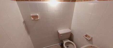 Un baño pequeño con inodoro, lavamanos y ducha.