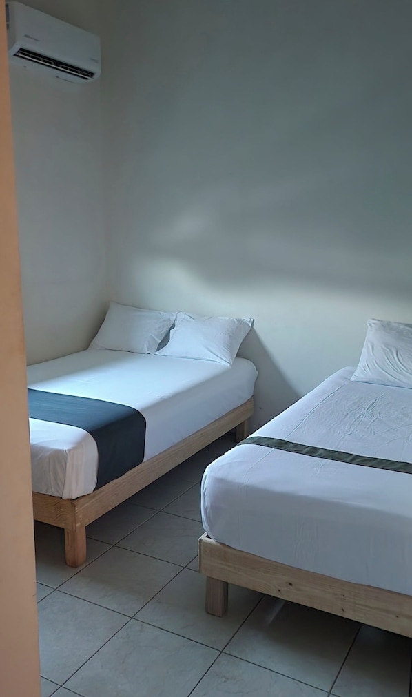 Una habitación con dos camas individuales, cada una con ropa blanca de cama y cabeceros de madera.