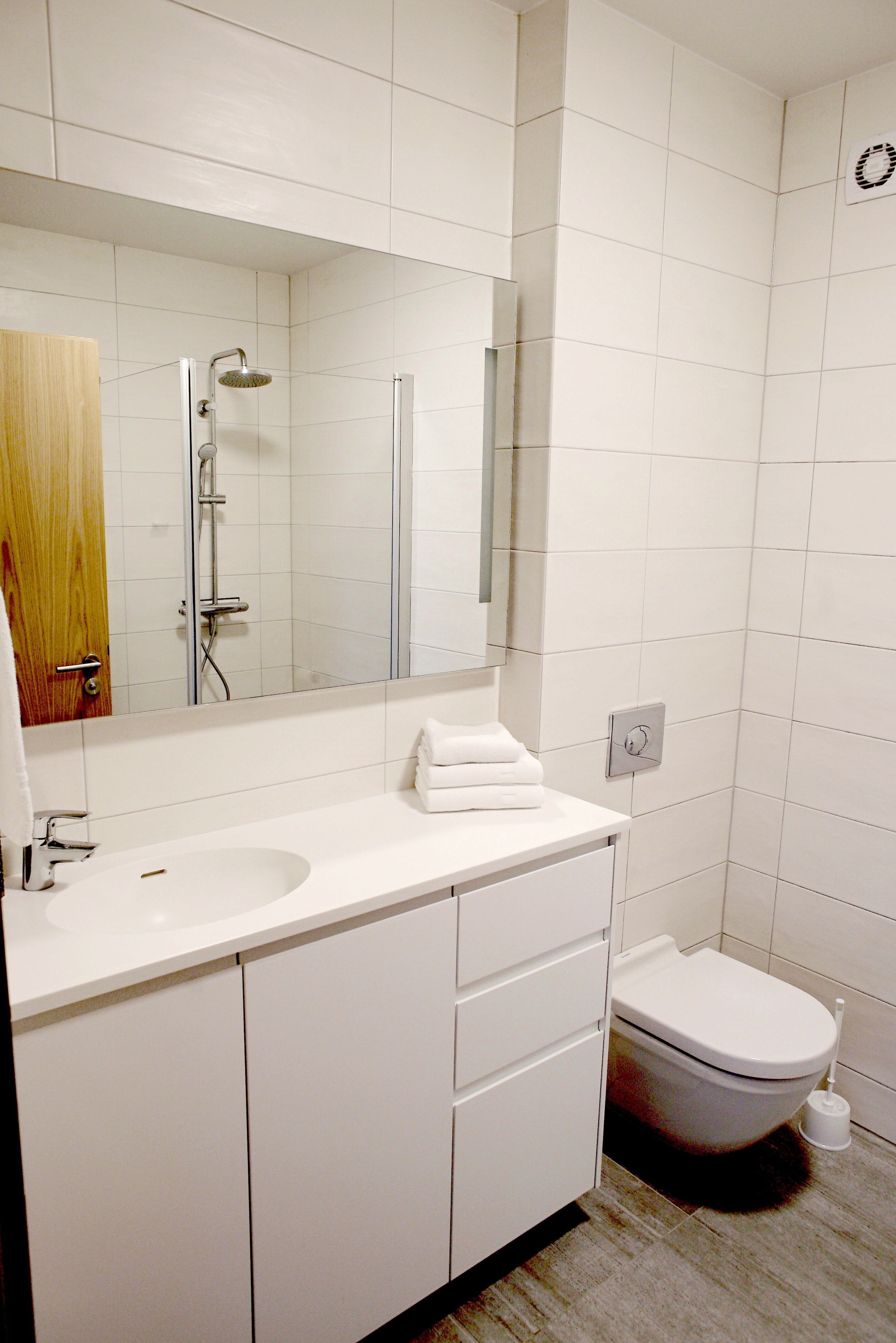 A modern bathroom with a white sink, mirror, and toilet.